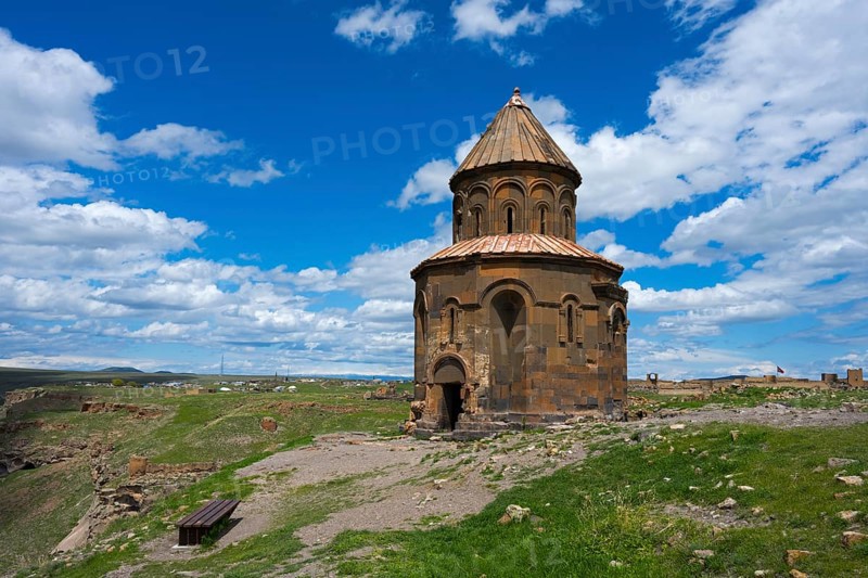 Old church on a hill under blue sky with clouds surrounded by grass and ruins, Armenian Church of Saint Gregory of Abughamrentz, Ani Archaeological Site, UNESCO World Heritage Site, Kars, Turkey