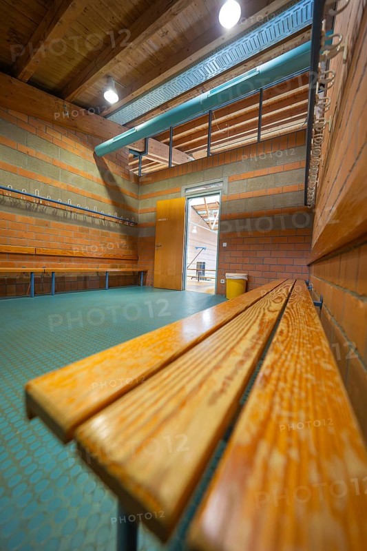 A light-flooded changing room with wooden benches and brick walls, turquoise floor, Schlehengäu Grund Schule Gechingen, Calw district, Germany