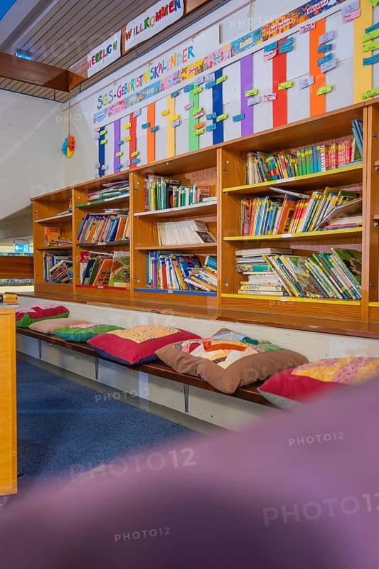Educational area with well-stocked bookshelf and colorful seating, Schlehengäu Grund Schule Gechingen, Calw district, Germany