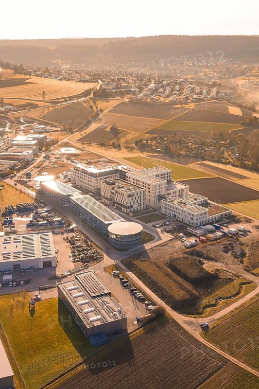 Aerial view of urban landscape in morning light with buildings, parks and fields, new hospital at Calw Health Campus, Calw district, Germany