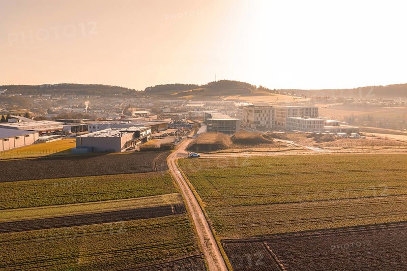 Extensive landscape with fields and buildings captured in low sunlight, new hospital at Calw Health Campus, Calw district, Germany