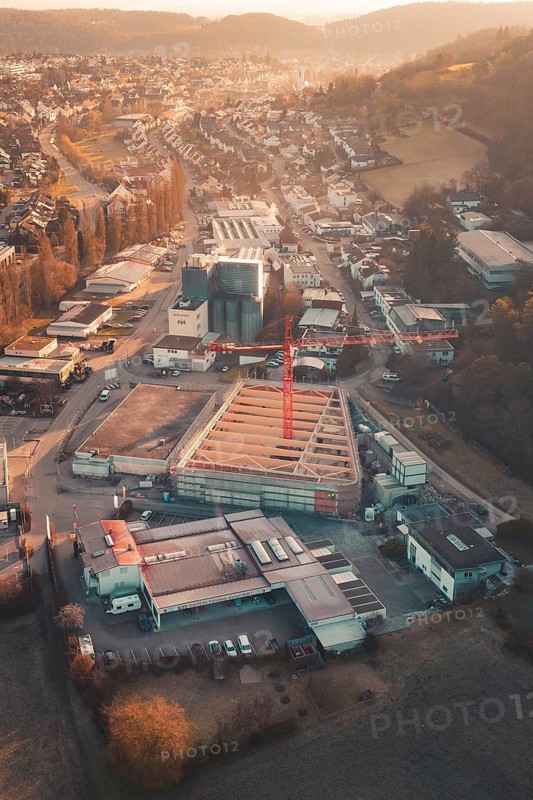 Aerial view of an urban building area with orange sky light and surrounding roads, Neubau Rewe, Aidlingen, Böblingen district, Germany