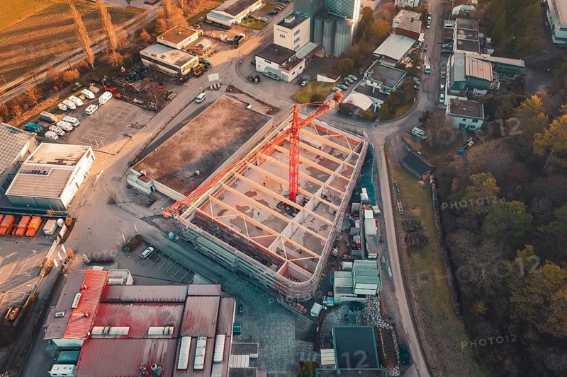 Aerial view of a construction site with crane in an urban area at sunset, surrounded by buildings and trees, Neubau Rewe, Aidlingen, Böblingen district, Germany