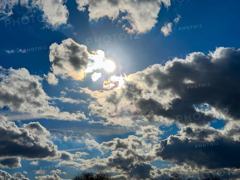Looking at the sun behind clouds Cumulus fractus against a blue sky, international
