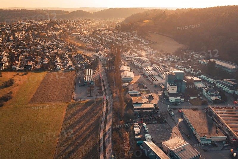 Commercial and residential areas blending with fields and hills under sunset glow, Aidlingen, Böblingen District, Germany