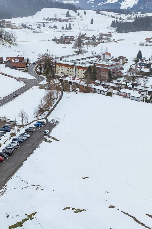 Snow-covered village with parking space in the midst of a winter landscape seen from the air, specialist clinic for psychosomatics and psychotherapy, Hochgrat Clinic, Stiefenhofen, Bavaria, Germany