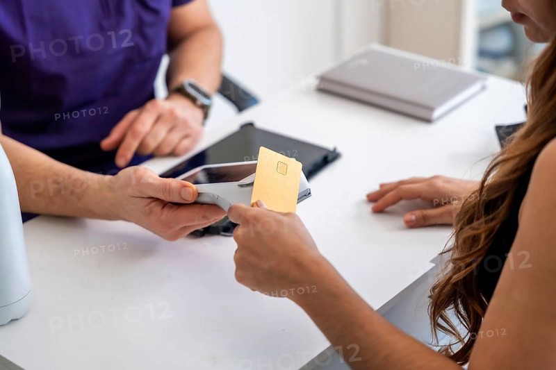 Patient paying for health services and medical recovery with a gold credit card at a contactless terminal, showing modern financial transactions in healthcare