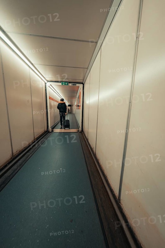 Long airport aisle with a traveller pulling a trolley bag, London, United Kingdom