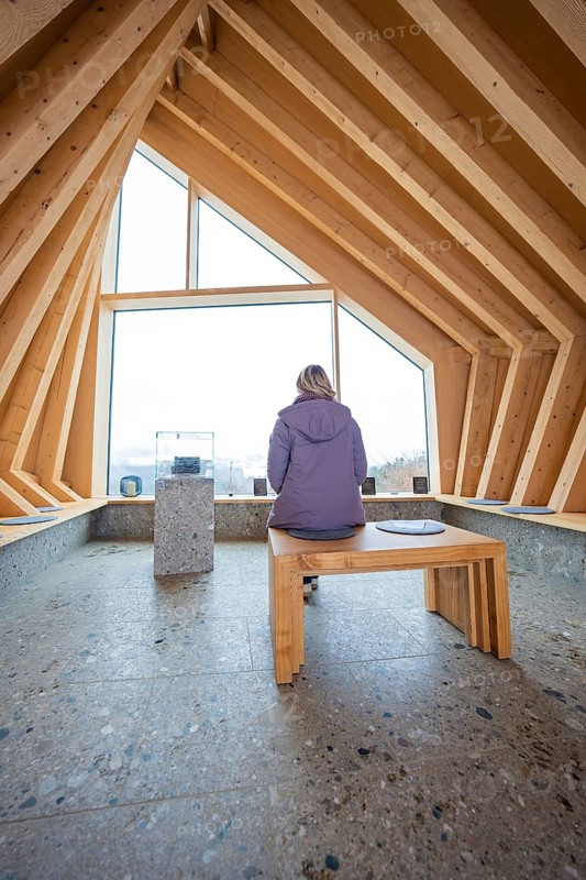 Person sitting on a bench in a modern wooden room with window view, Sinnraum, Oberreute, Allgäu, Bavaria, Germany
