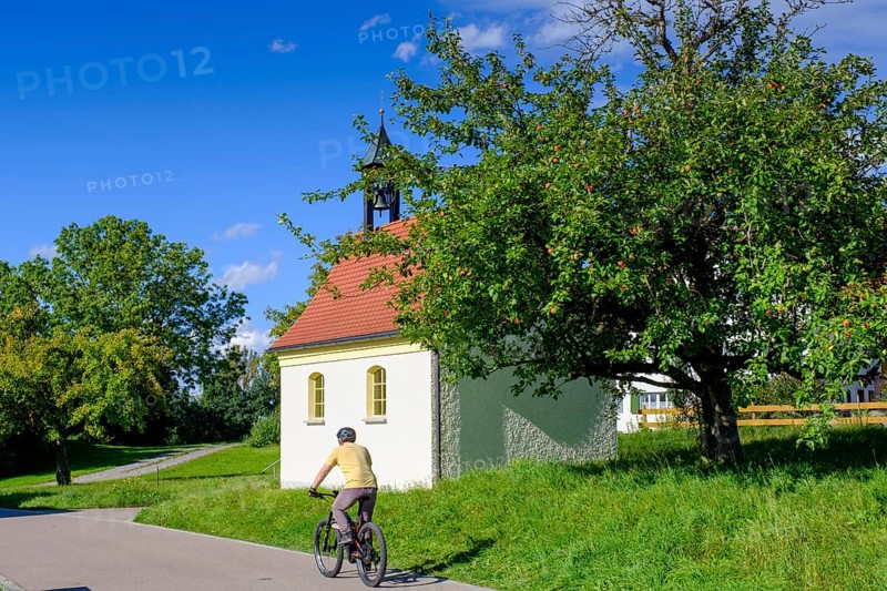 Cyclists in front of a chapel, Steingaden, near Sulzberg, Oberallgäu, Swabia, Bavaria, Germany