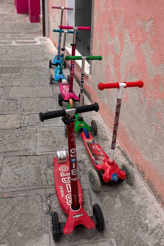 Colourful children's scooters in front of a kindergarten wall, Venice, Veneto, Italy