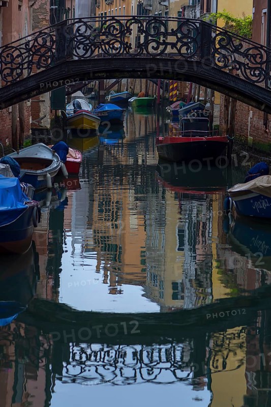 Wrought iron bridge reflected in the canal, Venice, Veneto, Italy