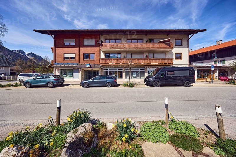 Volksbank Raiffeisenbank Oberbayern Südost eG, residential and commercial buildings, alpine buildings, façade with windows and balcony, building material wood, parking strips with cars, barrier bollard, flower bed, mountain, blue sky, cirrus clouds, cirrostratus clouds, Traunsteiner Straße, Inzell, district of Traunstein, Bavaria, Germany
