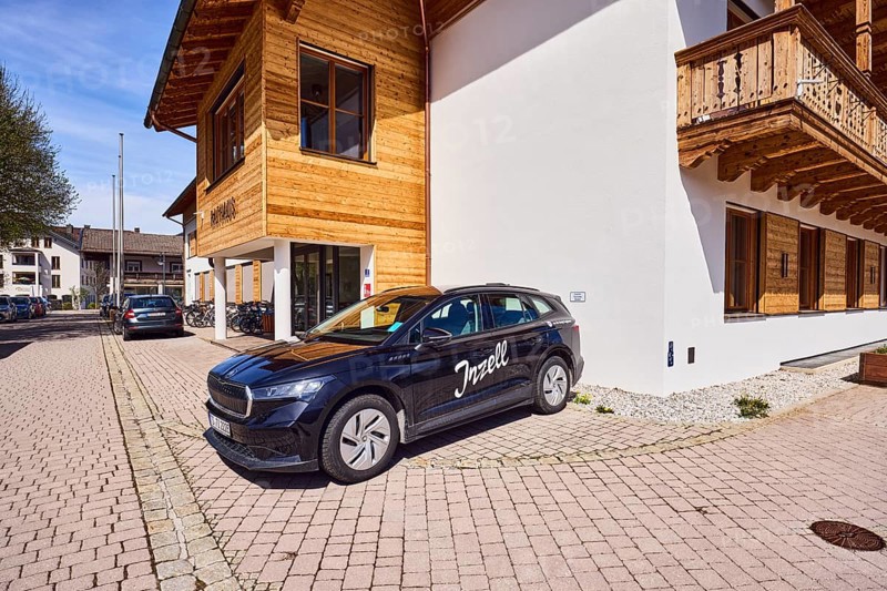 Car with advertising lettering Inzell, town hall, alpine buildings, commercial buildings, building material wood, entrance area, bare winter tree, blue sky, cirrostratus clouds, Rathausplatz square, Inzell, Traunstein district, Bavaria, Germany