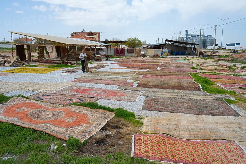 Open-air market with a variety of carpets spread across grasses and pebbles, Aksaray province, Turkey