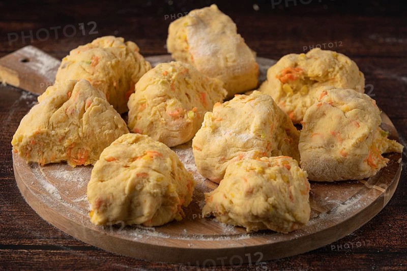 Several pieces of dough on a floured wooden board to prepare for baking