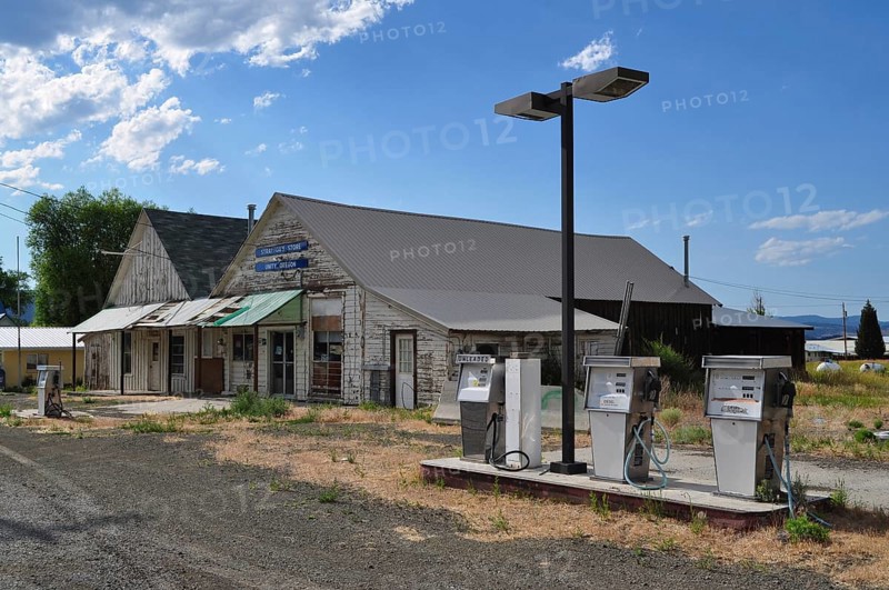 Abandoned gas station with old gas pumps in front of a rural shop, Unity, Oregon, USA