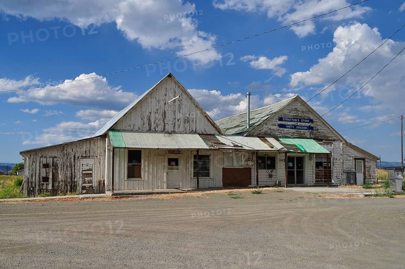 Two connected weathered buildings, Stratton's Store store, under blue sky with scattered clouds, Unity, Oregon, USA