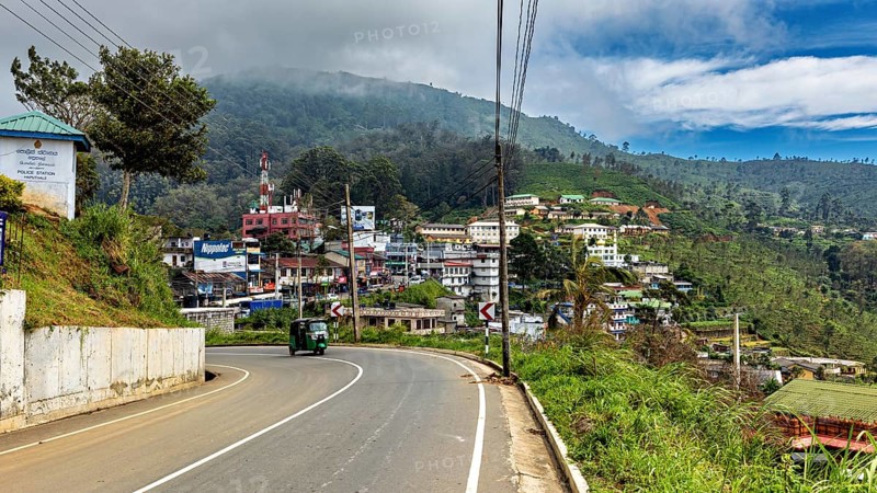 View of a curvy road in a village with hills and green countryside under a cloudy sky, The road on the edge of Horton Plans in Sri Lanka