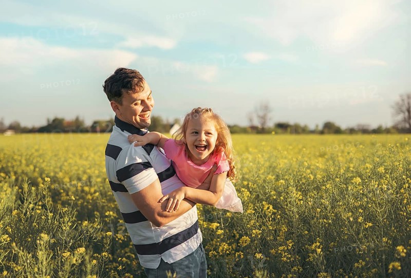 A young father and his little daughter play happily in nature in the summer. Happy parenting and childhood