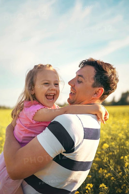 A young father and his little daughter play happily in nature in the summer. Happy parenting and childhood