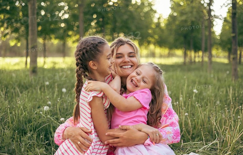 A young mother and two daughters have fun together outdoors in the summer. Family values