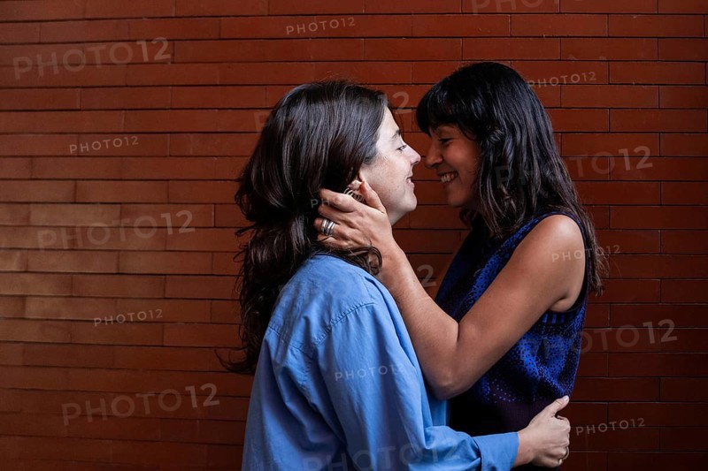 A loving embrace between a multiethnic lesbian couple, showcasing their connection and joy. The image highlights LGBTQIA+ pride and the beauty of diversity and love