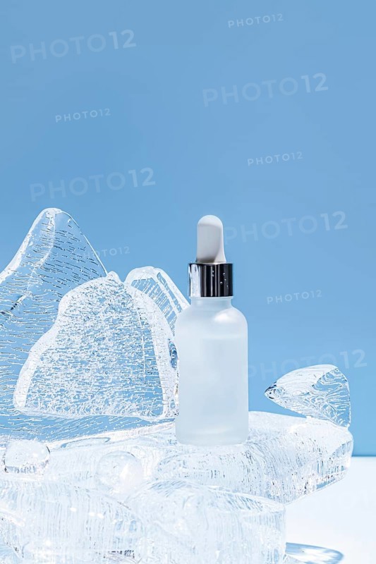 A serene image showcasing a clear serum bottle placed on an icy sculpture, illuminated with a soft blue backdrop, emphasizing freshness and purity