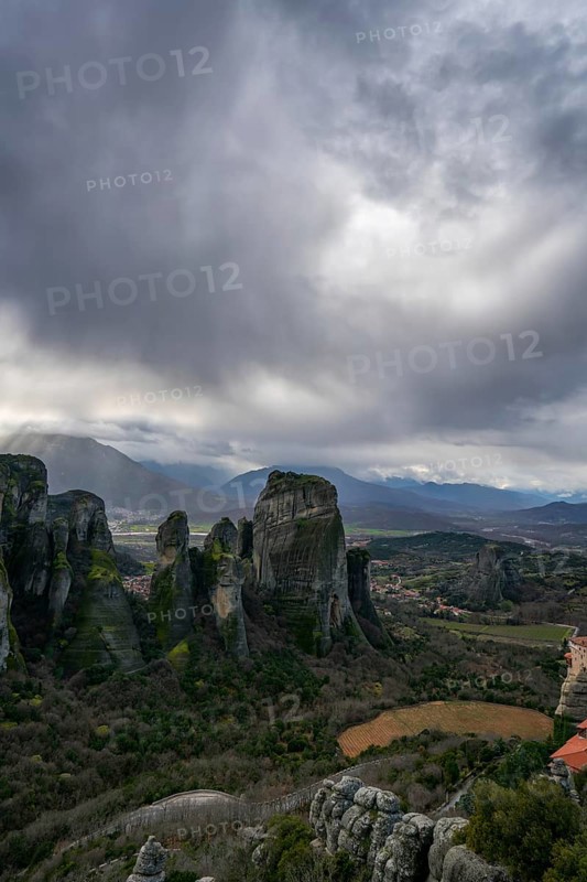 Panoramic view of Meteora's towering rock formations and ancient monasteries in Kalabaka, Greece, under a moody sky. A UNESCO World Heritage Site of spiritual and natural beauty