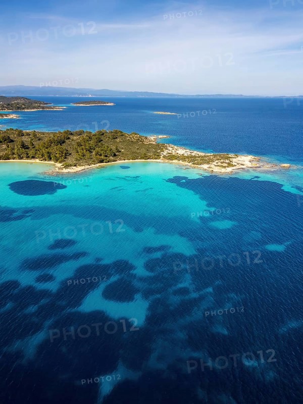 Aerial view of Diaporos Island and Karydi Beach, Greece, with bright turquoise waters, green forests, and rocky shores. A breathtaking Mediterranean coastal scene under clear skies
