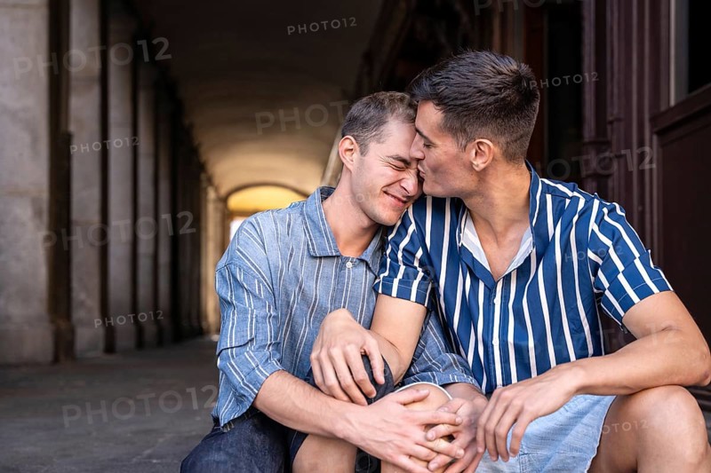 A loving gay couple shares an affectionate moment on the picturesque streets of Madrid. Their embrace reflects pride and a celebration of their relationship