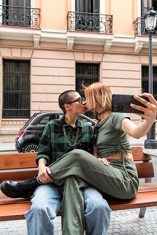 Colombian lesbian couple captures a loving kiss on a city bench, showcasing affection and identity. A celebration of LGBTQIA+ love, diversity, and acceptance