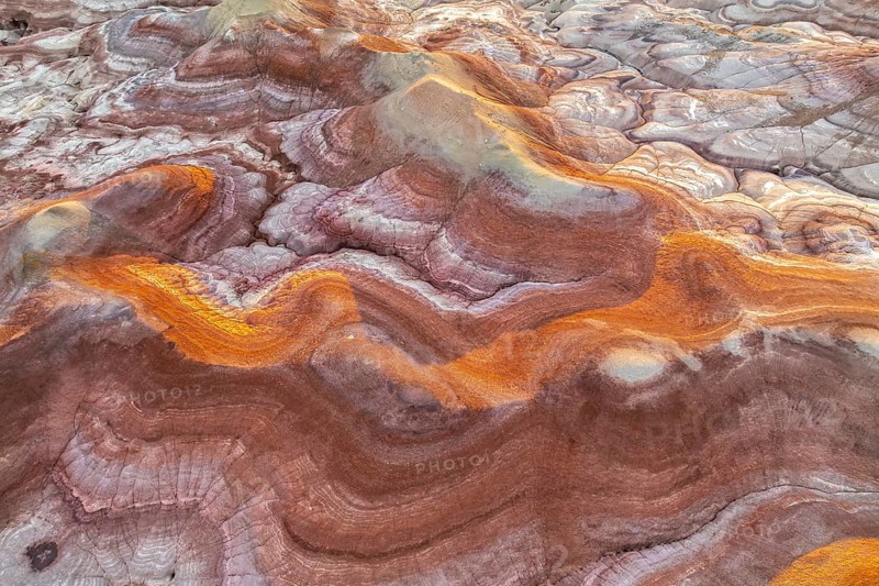 Capture of Utah's bentonite formations, showcasing swirling patterns and vibrant hues of gold and pink. Nature's palette highlights geological wonders across desert terrain