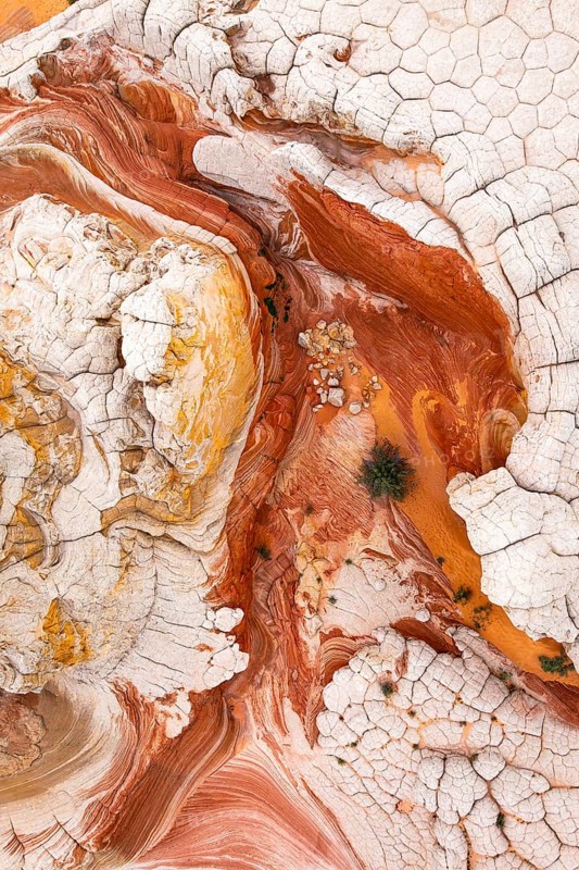 This striking aerial image captures the complex patterns of red and white rock formations. The textures and curves create an abstract natural landscape