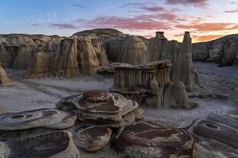 Captivating sunset view of the surreal, eroded rock formations in the Bisti/De-Na-Zin Wilderness, New Mexico, displaying a breathtaking landscape under a colorful sky