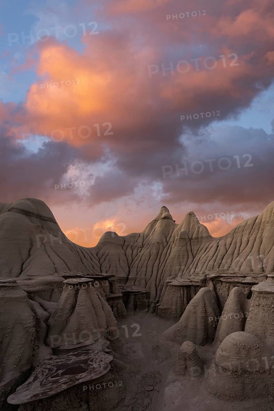 Surreal landscape at sunset featuring the unique hoodoos of Bisti/De-Na-Zin Wilderness in New Mexico, USA, under a vibrant sky