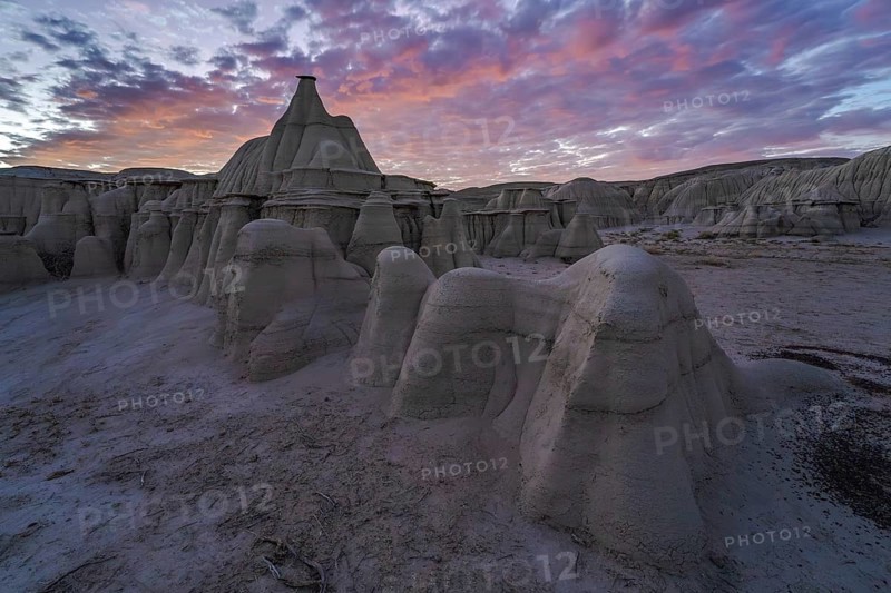 Dramatic sunset illuminating the unique rock formations of Bisti/De-Na-Zin Wilderness in New Mexico, USA, showcasing nature's artistry in the desert landscape