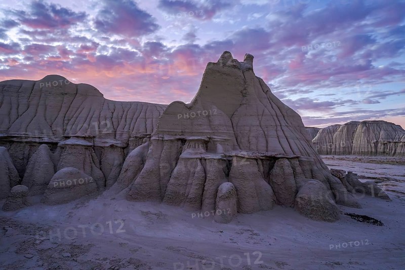 Sunset casts a soft glow over the dramatic and weathered sandstone formations of the Bisti/De-Na-Zin Wilderness in New Mexico, highlighting its unique geological features