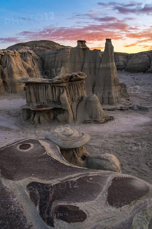 Majestic hoodoos and textured rock formations glow under a sunset sky in Bisti/De-Na-Zin Wilderness, New Mexico, USA, showcasing nature's artistry