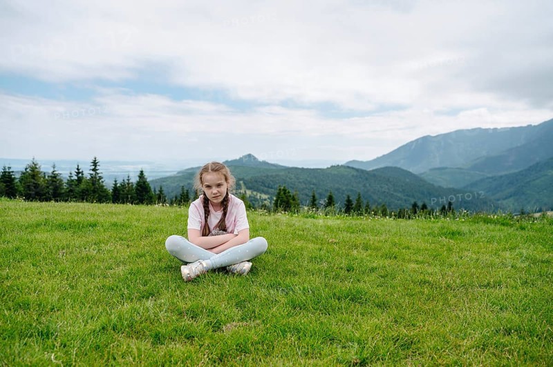 Young girl resting on a grassy hill with a stunning view of the Belianske Tatras, seen from Bachledka in Slovakia