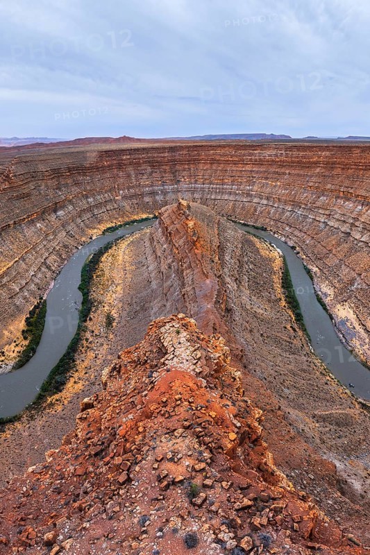 Stunning aerial view of a San Juan canyon featuring a winding river carving through layered rock formations. The rich earthy tones highlight the geological wonders of the landscape in Utah, USA