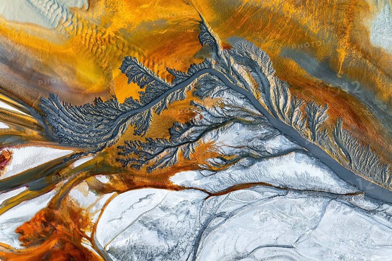 Explore intricate fractal mud textures with vivid earthy tones. This aerial view showcases stunning abstract patterns resembling a fusion of organic and geological formations