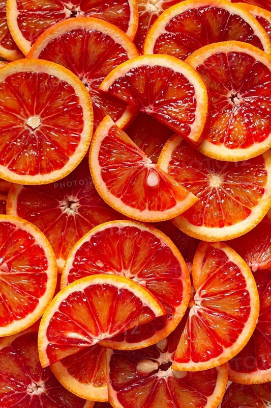 A close-up view of freshly sliced blood oranges revealing vibrant red and orange hues. The juicy segments create a pattern, highlighting natural beauty and texture