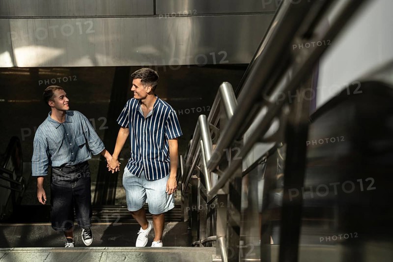 A happy gay couple, hand in hand, strolling up a stairway in the vibrant streets of Madrid. Captures a moment of joy and connection, emphasizing love and pride