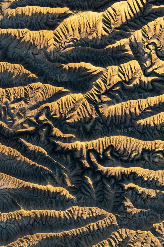 Capturing the intricate golden textures of Caineville Mesa, Utah, this aerial view reveals the stunning patterns and ridges formed by natural erosion in a desert landscape