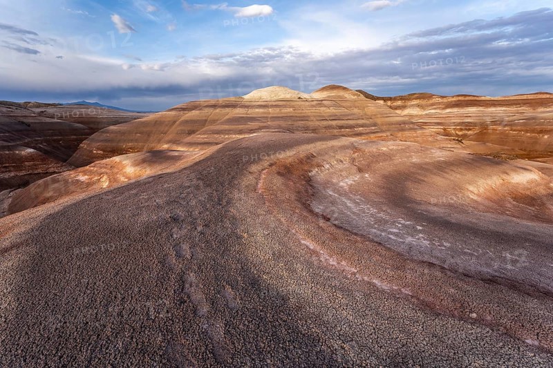 Explore the stunning bentonite hills in Hanksville, Utah. These unique formations showcase layered sedimentary patterns and vivid natural colors, under a vast, open sky