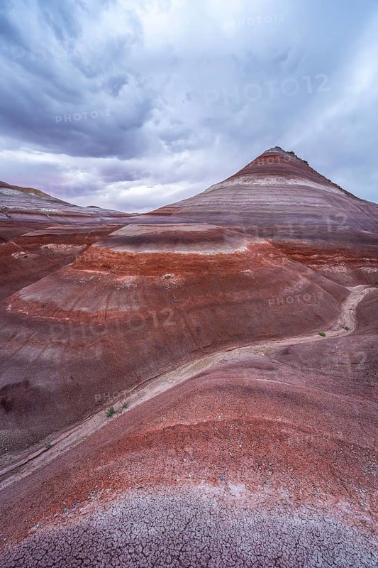 Explore the stunning layers and vibrant colors of the Hanksville Bentonite Hills in Utah. These sedimentary formations create a mesmerizing natural landscape under a dynamic sky