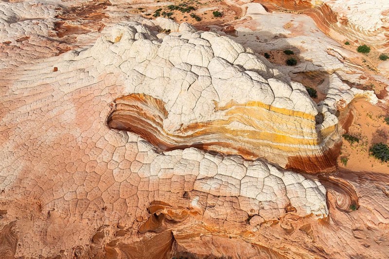 Aerial view of sandstone formations showcasing layered textures and vibrant colors in White Pocket. Unique patterns and natural erosion highlight the beauty of desert geology in Arizona, USA