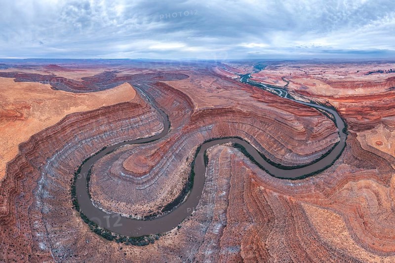 Captivating aerial view of a river winding through the dramatic, layered San Juan canyon. The contrasting colors of the rock formations and water create a stunning natural landscape in Utah, USA