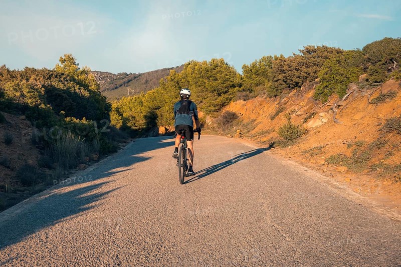 Back view of an unrecognizable male cyclist riding on a quiet road through the hills near Faro Camarinal, Zahara de los Atunes, Cadiz